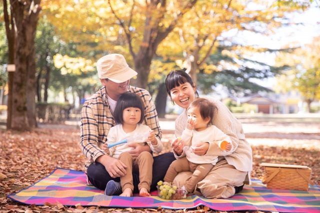 紅葉の下でぶどうを食べる家族の写真